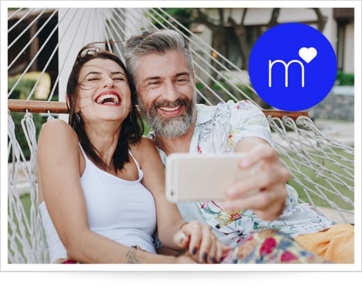 Couple taking ‌selfie with Match dating ⁢app logo‌ overlay